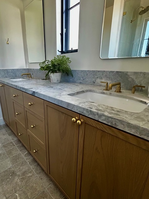 Dual sink vanity with marble countertop and brass faucets installed by So-Cal Plumbing