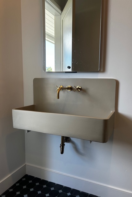 Wall-mounted concrete sink with exposed brass faucet installed by So-Cal Plumbing
